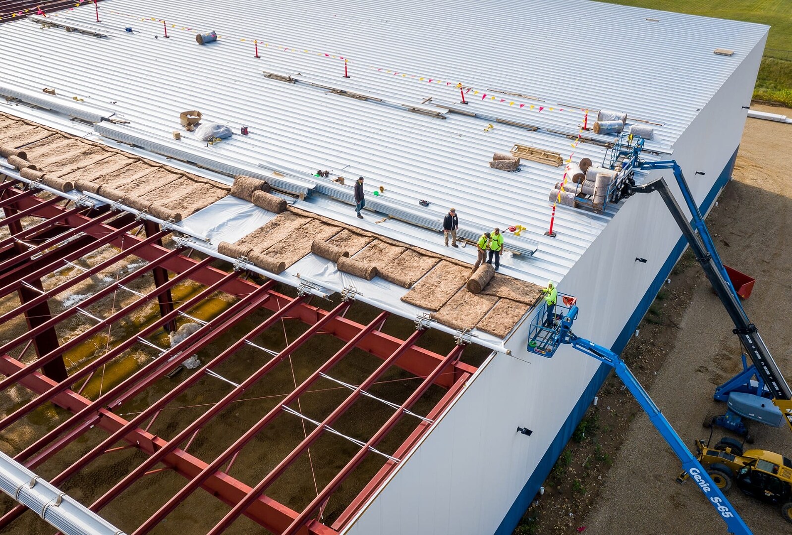 Aerial view of large-scale commercial metal roof installation by Impact Exteriors - crew and lift equipment on-site