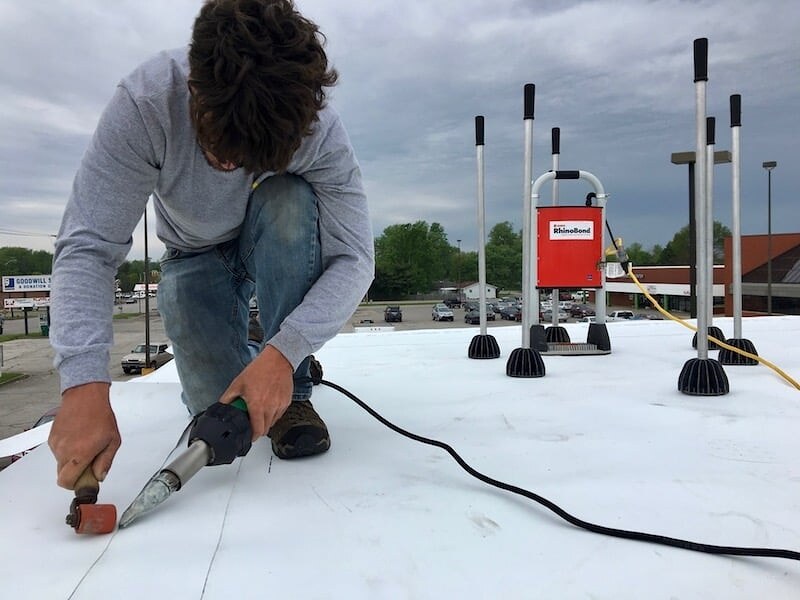 RhinoBond induction welding tool in use on commercial TPO roof - no fasteners penetrate the membrane